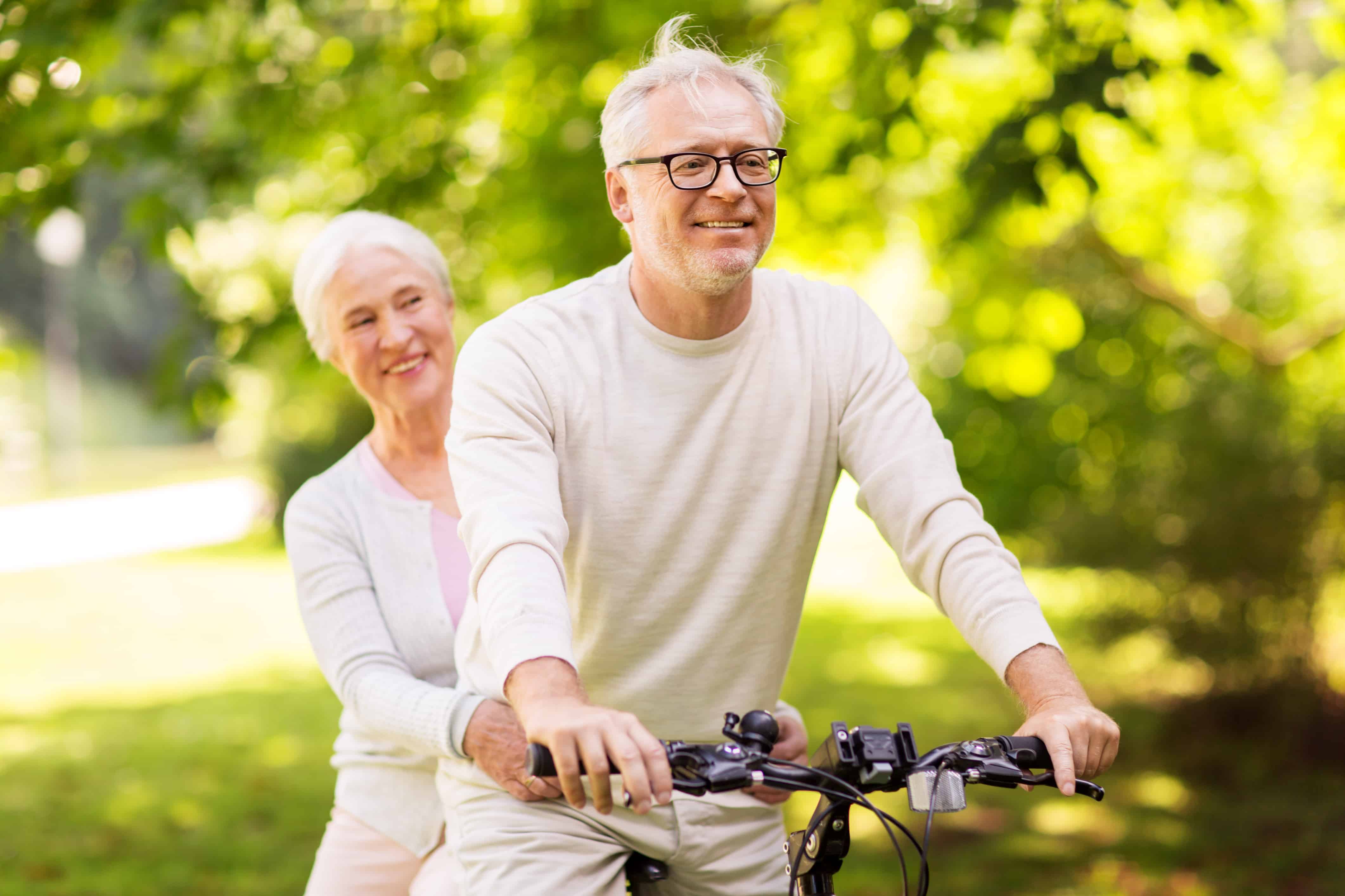Two seniors riding on a bike together